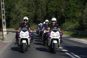 Policjanci na motocyklach jadą w dwóch kolumnach koło siebie.